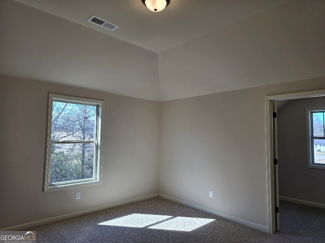 spare room with carpet floors, visible vents, a wealth of natural light, and lofted ceiling