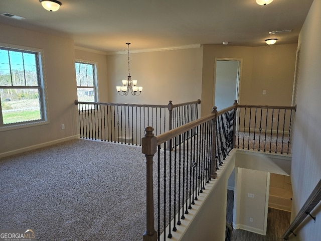 interior space featuring baseboards, visible vents, ornamental molding, an inviting chandelier, and carpet flooring