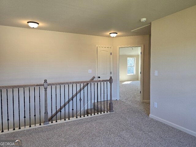 hallway with carpet floors, baseboards, and an upstairs landing