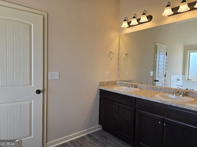 full bath featuring wood finished floors, a sink, baseboards, and double vanity