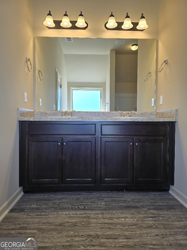 full bath with double vanity, wood finished floors, visible vents, and baseboards