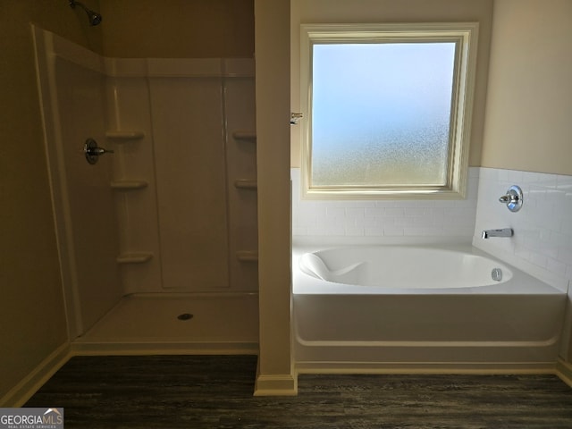 bathroom featuring a garden tub, a shower, and wood finished floors