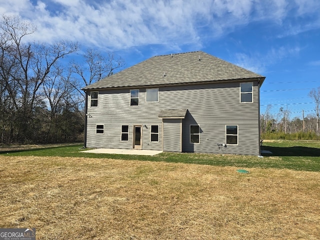 rear view of house featuring a lawn and a patio