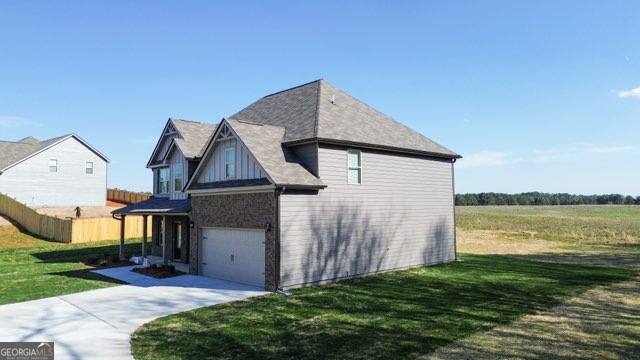 view of side of home with a garage, concrete driveway, a yard, and fence