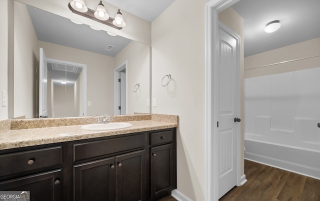 bathroom with wood-type flooring, vanity, and  shower combination