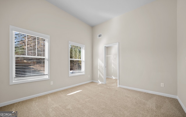 unfurnished room with light carpet and lofted ceiling