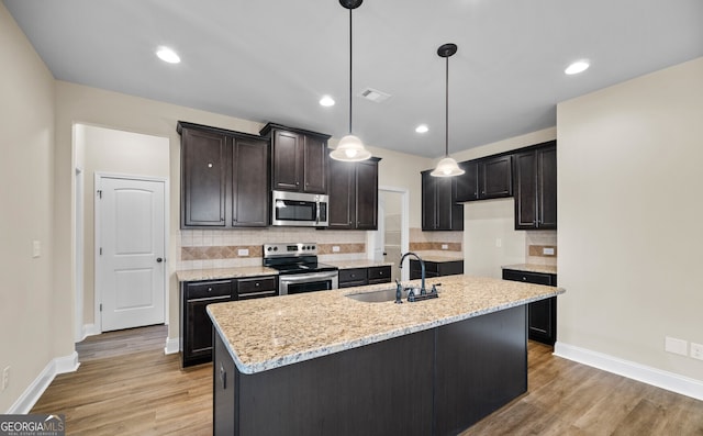 kitchen with appliances with stainless steel finishes, a center island with sink, light hardwood / wood-style floors, and sink