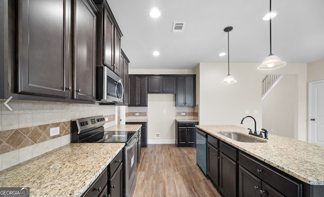 kitchen with appliances with stainless steel finishes, pendant lighting, a center island with sink, hardwood / wood-style floors, and sink