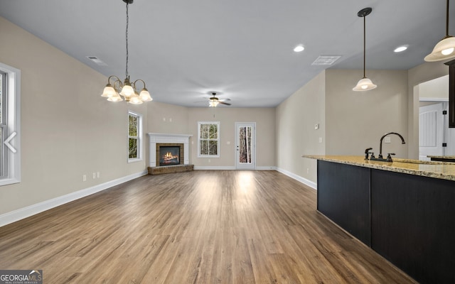 unfurnished living room with ceiling fan with notable chandelier, hardwood / wood-style floors, and sink