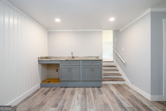 bar featuring light wood-type flooring, gray cabinets, crown molding, and sink