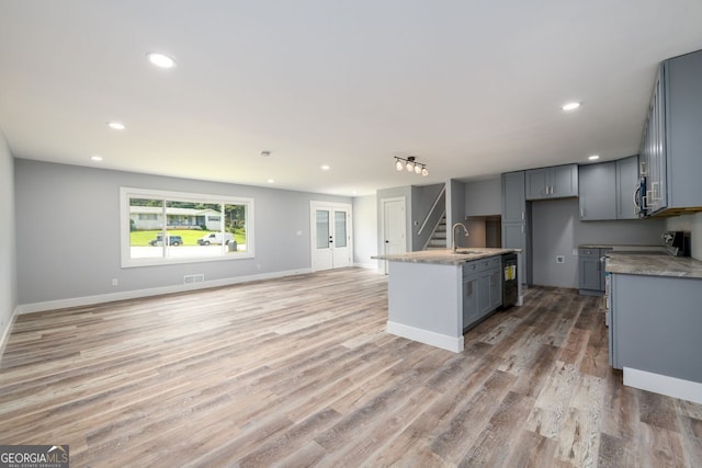 kitchen featuring hardwood / wood-style floors, gray cabinetry, an island with sink, and sink