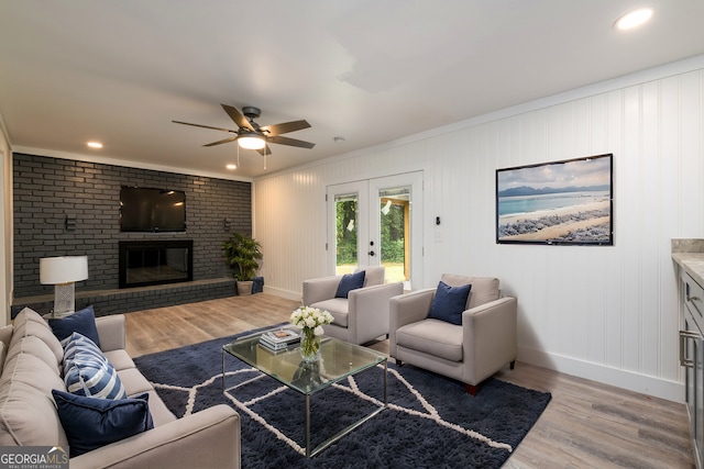 living room with light hardwood / wood-style flooring, ceiling fan, ornamental molding, and a fireplace