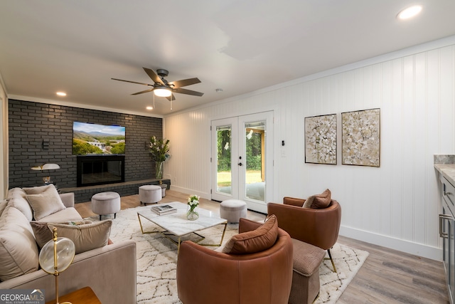 living room with hardwood / wood-style floors, ceiling fan, ornamental molding, and a brick fireplace