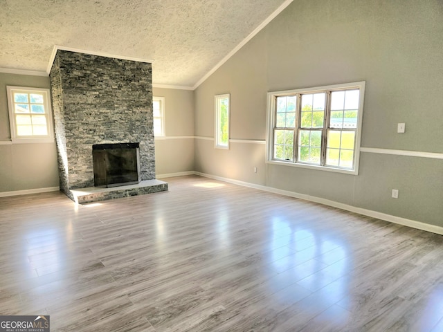 unfurnished living room with a stone fireplace, crown molding, a textured ceiling, and hardwood / wood-style flooring