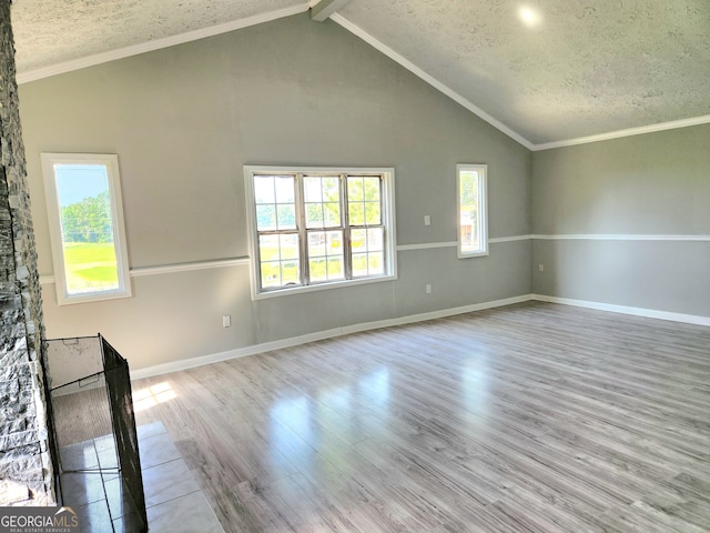 unfurnished living room with light hardwood / wood-style floors, a textured ceiling, and vaulted ceiling