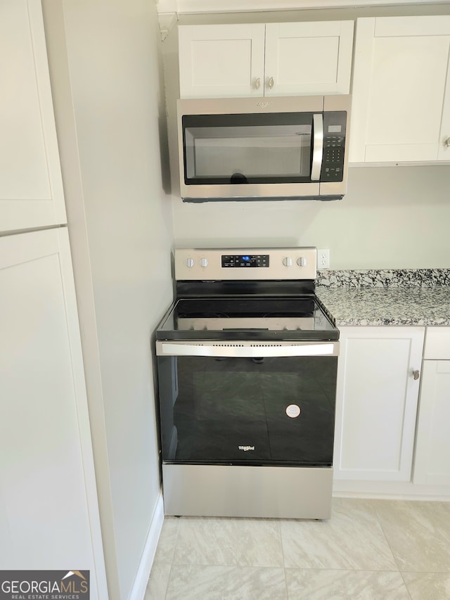 kitchen with white cabinetry, light tile patterned flooring, light stone countertops, and stainless steel appliances