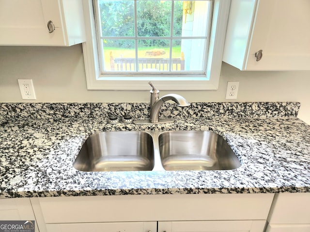 interior details featuring sink, white cabinets, and stone countertops