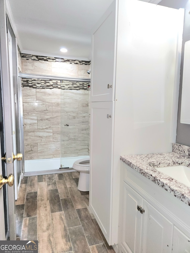 bathroom with walk in shower, hardwood / wood-style flooring, toilet, and vanity