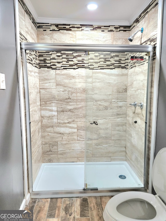 bathroom with wood-type flooring, crown molding, toilet, and an enclosed shower