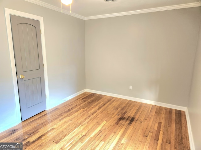 empty room featuring light wood-type flooring and ornamental molding