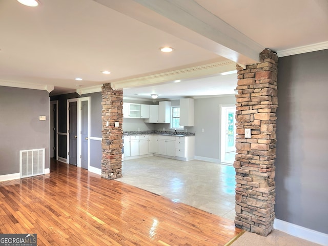 unfurnished living room with ornamental molding, sink, ornate columns, and light tile patterned flooring