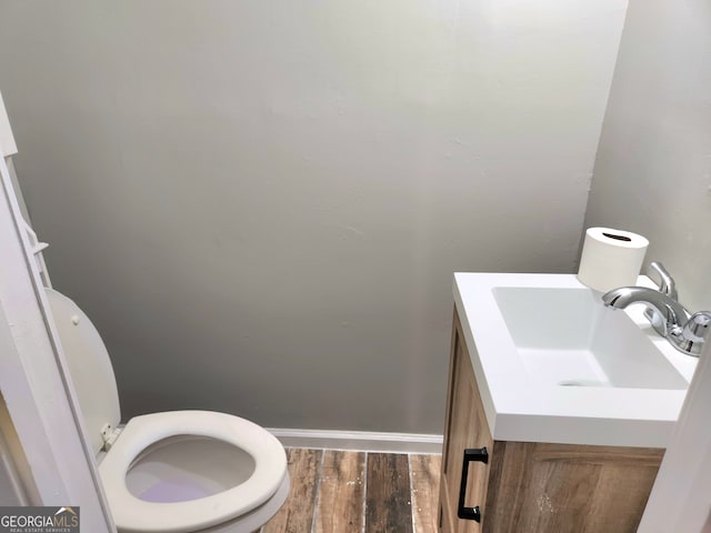 bathroom with hardwood / wood-style flooring, toilet, and vanity