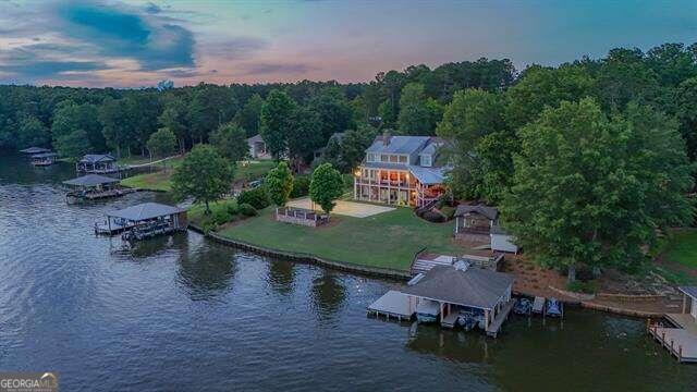 aerial view at dusk with a water view and a view of trees