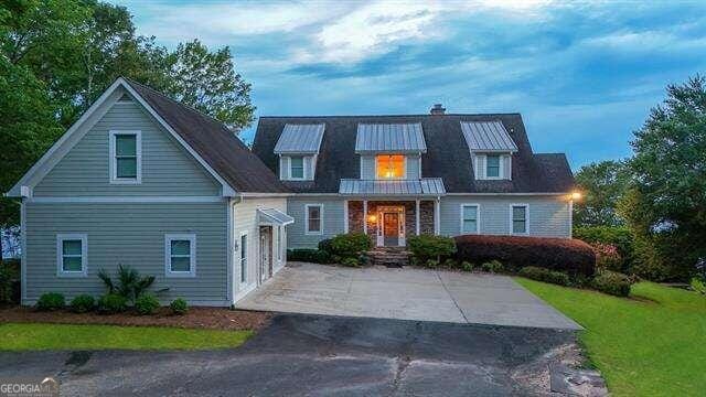 view of front of property featuring driveway, a balcony, a chimney, metal roof, and a standing seam roof