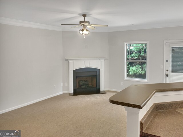 unfurnished living room featuring ceiling fan, carpet, and ornamental molding