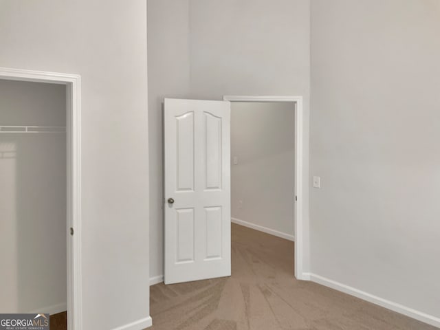 unfurnished bedroom featuring a closet and light colored carpet