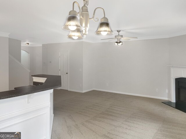 unfurnished living room featuring ceiling fan with notable chandelier and carpet floors