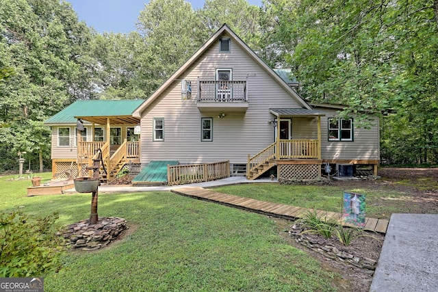 rear view of property with a balcony, a deck, and a yard