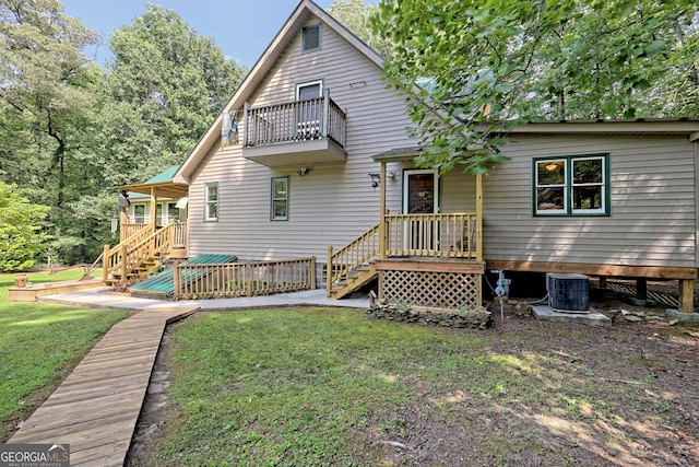 rear view of house with a balcony, a lawn, and cooling unit