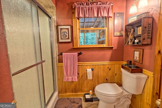 bathroom featuring toilet, a shower with door, and wooden walls