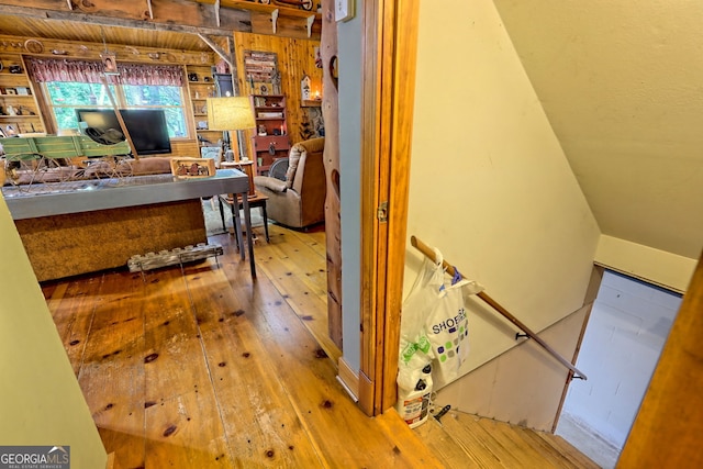 corridor featuring light hardwood / wood-style flooring and wooden walls