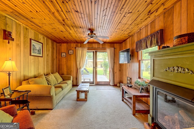 carpeted living room with wood ceiling, wood walls, and ceiling fan