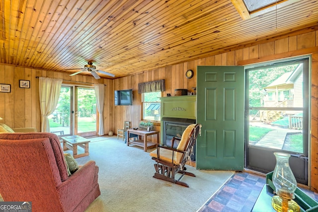 carpeted living room with wood walls, ceiling fan, and wood ceiling