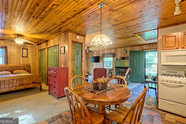 dining area featuring wooden walls, wooden ceiling, and ceiling fan with notable chandelier