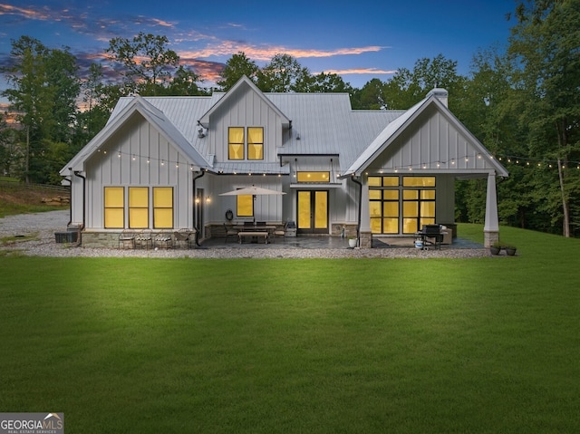 back house at dusk with a patio area, central AC, and a yard