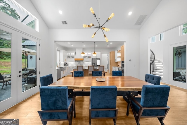 dining space featuring high vaulted ceiling, french doors, light hardwood / wood-style flooring, and a notable chandelier