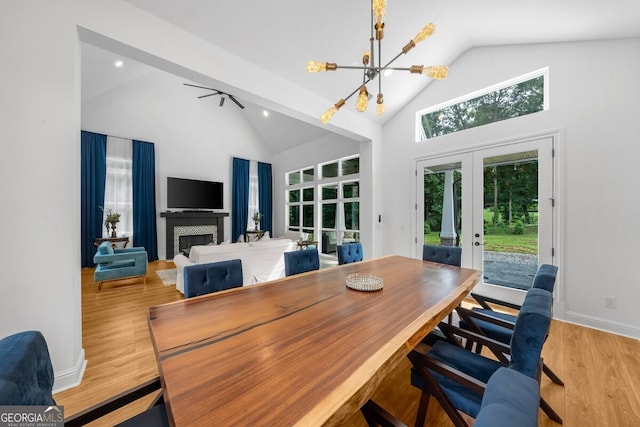 interior space with french doors, a chandelier, light hardwood / wood-style floors, a tile fireplace, and high vaulted ceiling