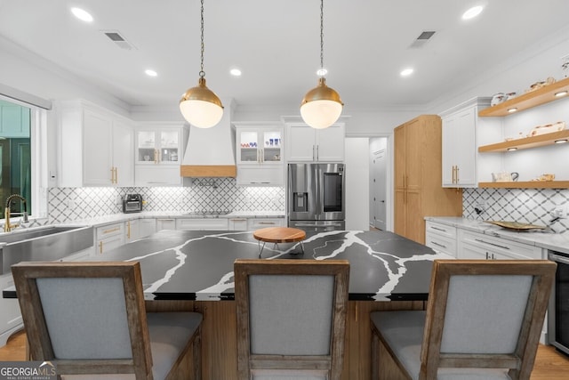 kitchen featuring decorative backsplash, white cabinets, custom exhaust hood, and stainless steel fridge with ice dispenser