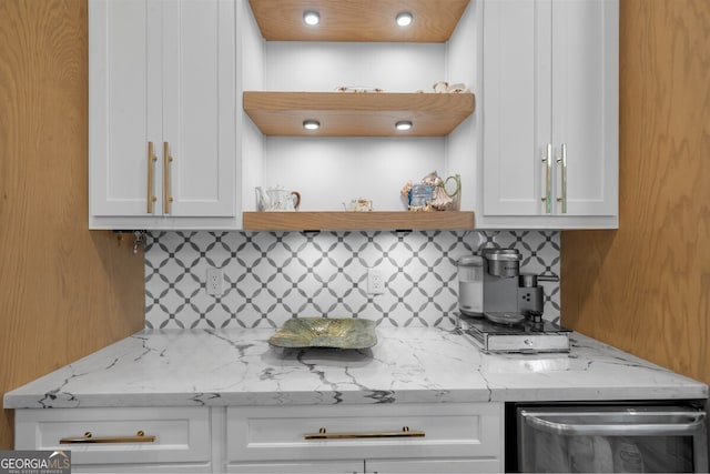 kitchen with stainless steel dishwasher, light stone countertops, white cabinets, and backsplash