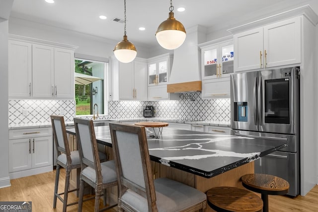 kitchen with light hardwood / wood-style flooring, white cabinets, backsplash, stainless steel refrigerator with ice dispenser, and ornamental molding