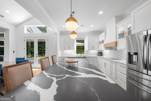 kitchen with white cabinetry, stainless steel refrigerator with ice dispenser, decorative backsplash, french doors, and light hardwood / wood-style flooring