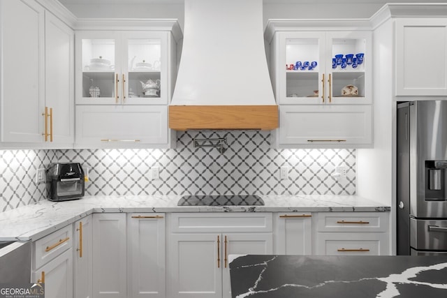 kitchen featuring white cabinetry, backsplash, custom range hood, and stainless steel refrigerator with ice dispenser