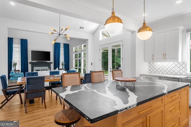 kitchen with white cabinetry, lofted ceiling, light hardwood / wood-style flooring, a center island, and decorative backsplash