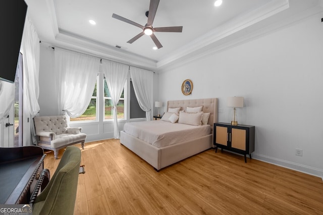 bedroom featuring light hardwood / wood-style flooring, ceiling fan, and a raised ceiling