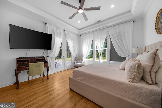 bedroom with french doors, light hardwood / wood-style floors, access to outside, ceiling fan, and a raised ceiling