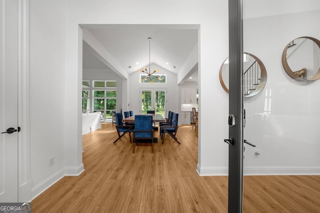 interior space featuring vaulted ceiling, french doors, light wood-type flooring, and an inviting chandelier